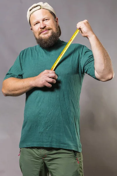 Joyful baard ambachtsman in groen t-shirt met tape maatregel — Stockfoto