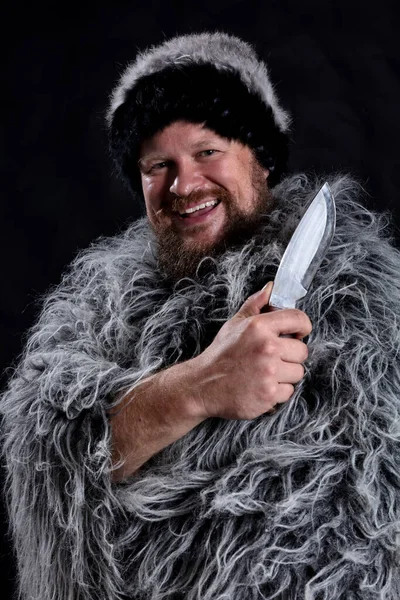 Caçador barbudo vestido com um manto de pele e chapéu de pele com faca — Fotografia de Stock