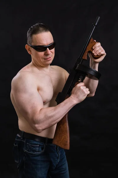 Mature man in sunglasses and naked torso with tommy gun — Stock Photo, Image