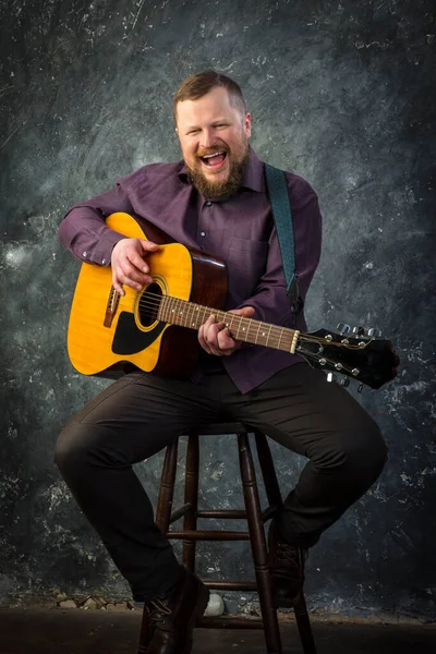 Mature musician plays acoustic guitar emotional studio portrait. — Stock Photo, Image