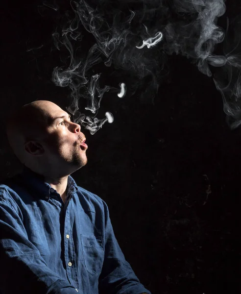 Hombre calvo maduro fumando, retrato sobre fondo negro. — Foto de Stock