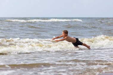 Genç neşeli çocuk deniz dalgalarında eğleniyor..