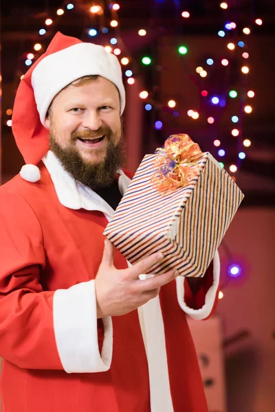 Brodaty mężczyzna ubrany w strój Świętego Mikołaja z prezentami — Zdjęcie stockowe