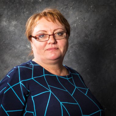 Mavi elbiseli orta yaşlı kadın gülümsüyor.