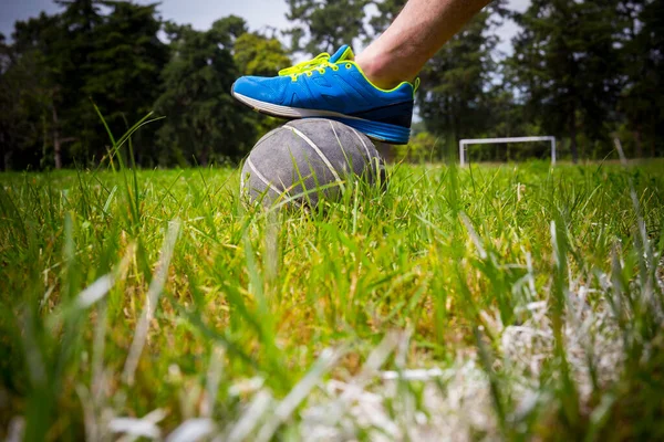 Jogador de futebol chutando a bola no campo verde naturak — Fotografia de Stock