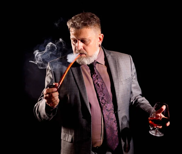 Fast säker skäggig man i kostym med glas whisky rökning pipa — Stockfoto