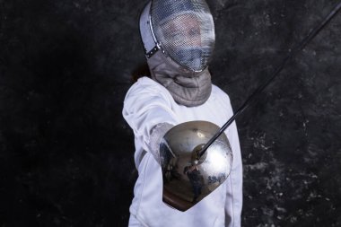 Üniformalı, çişli ve kasklı eskrimci kız.