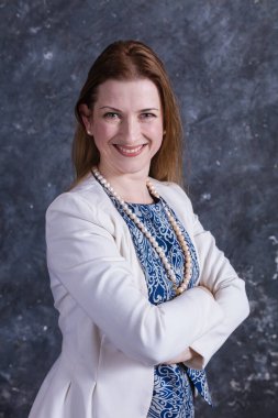 Mavi elbiseli ve beyaz ceketli neşeli orta yaşlı kadın.