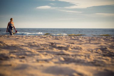 Genç ve güzel bir kadın kumsalda yürüyor