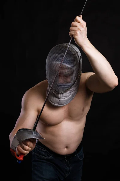 Matured man with naked muscular torso in fencing helmet and epee — Stock Photo, Image