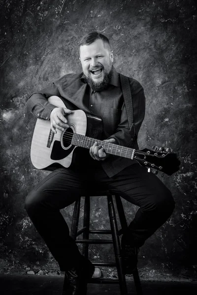 Mature musician plays acoustic guitar emotional studio portrait. — Stock Photo, Image