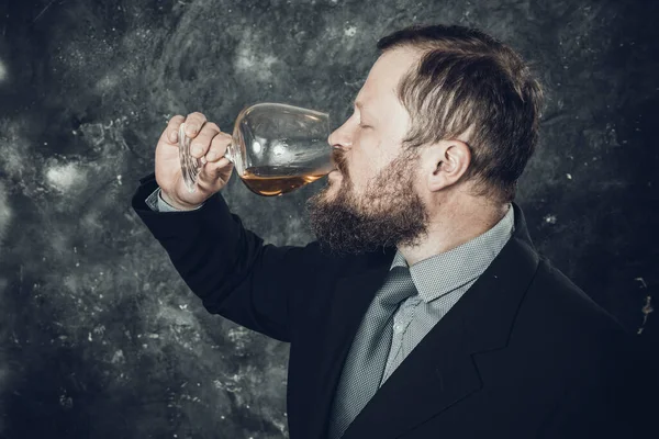 Homme barbu solide en costume dégustation de whisky dans un verre — Photo