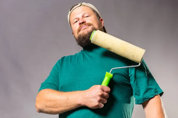 Fröhlicher bärtiger Handwerker im grünen T-Shirt hat Spaß mit Farbroller — Stockfoto