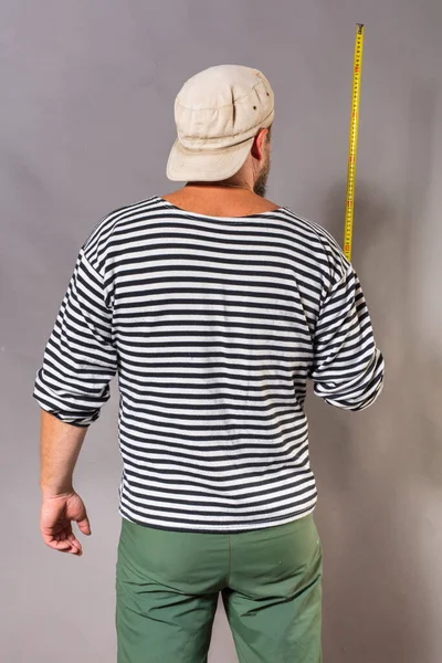 Fröhlicher bärtiger Handwerker mit Maßband-Studioporträt auf grauem Hintergrund. — Stockfoto