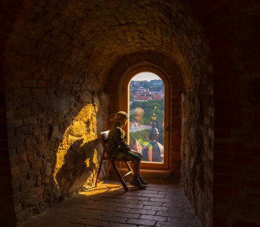 Çocuk Vilnius 'un eski taş pencere manzarasına bakıyor..