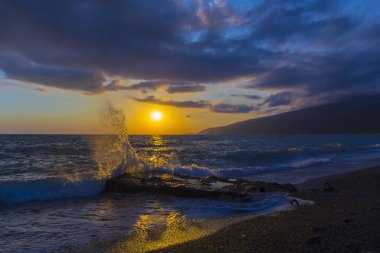 Gün batımında dalgalarla güzel bir kıyı sahnesi