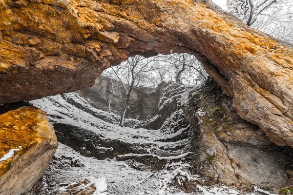 Arco de piedra en las montañas del Cáucaso con la primera nieve en otoño. — Foto de Stock