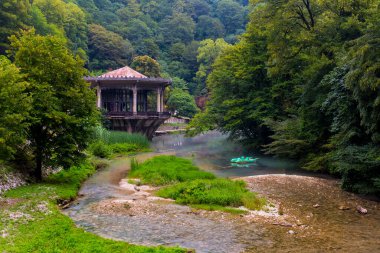 Eski pavyonu ve sudaki teknesi olan güzel bir manzara.