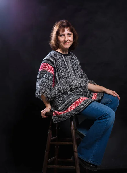 Alegre mujer de 40 años vestida con jeans y poncho retrato de estudio —  Fotos de Stock