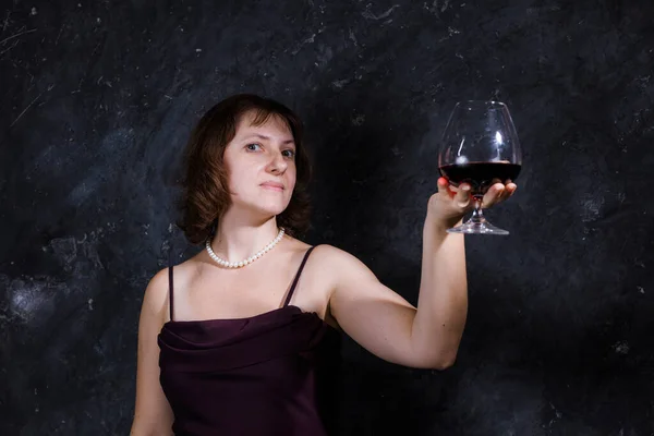 Cheerful 40 years old woman in classic dress with glass of wine — Stock Photo, Image