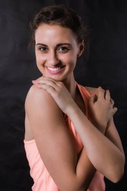 Siyah arka planda spor kıyafetleri içinde güzel bir genç kadın..