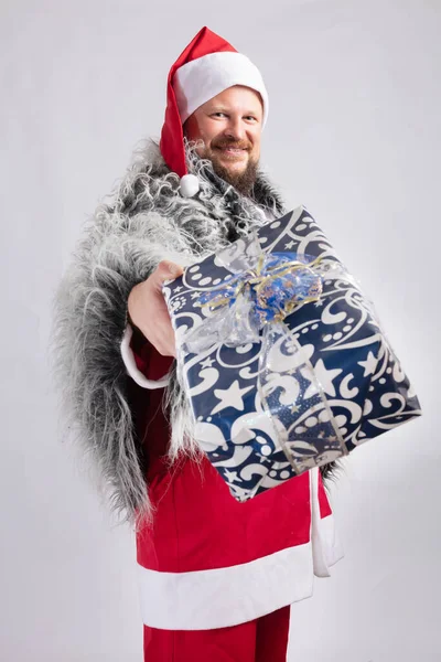 Χαρούμενος Άγιος Βασίλης ντυμένος με γούνινο δέρμα που προσφέρει ένα δώρο — Φωτογραφία Αρχείου
