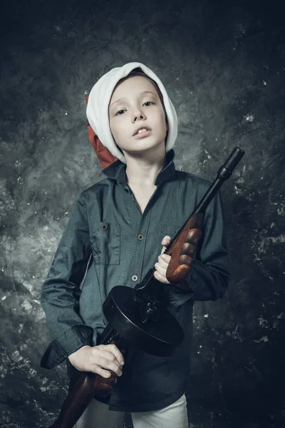 Pequeno Papai Noel de chapéu vermelho com uma arma — Fotografia de Stock
