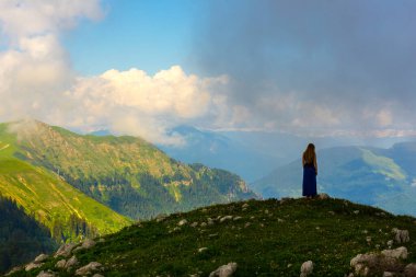 Kafkasya dağlarında güzel bir dağ manzarası. Tepenin tepesinde duran bir kadın var.
