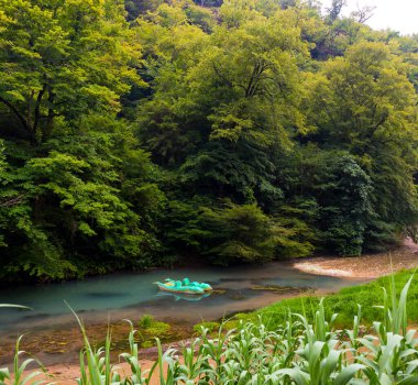 Sakin bir nehri ve sudaki teknesi olan güzel bir manzara.