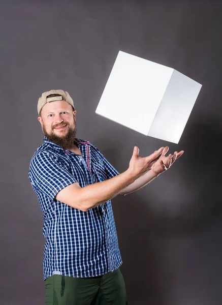 Χαρούμενος γενειοφόρος άνδρας σε πουκάμισο με λευκό αντικείμενο μοιάζει με κύβο — Φωτογραφία Αρχείου