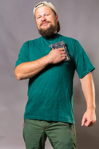 Gioioso artigiano barbuto in t-shirt verde divertirsi con pistola fiocco — Foto Stock