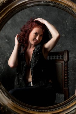 Güzel genç bir kadın aynaya bakıyor.