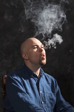 Olgun kel adam sigara içiyor, siyah arka planda portre çiziyor..