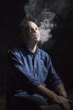 Olgun kel adam sigara içiyor, siyah arka planda portre çiziyor..