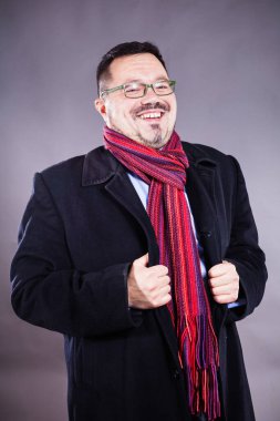 Gözlüklü, ceketli ve mendilli, neşeli bir adam.