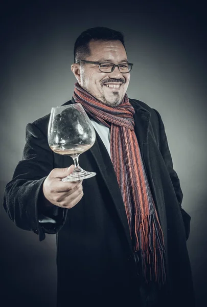Pevný veselý muž v kabátě a kapesníku, stojící se sklenicí vína — Stock fotografie