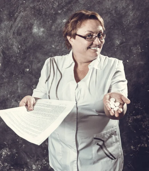 Mujer de mediana edad farmacéutica en bata médica ofrece las tabletas —  Fotos de Stock