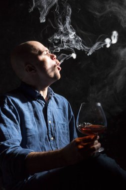 Bir bardak viski ve dumanlı stüdyo portresi olan katıksız kel bir adam..