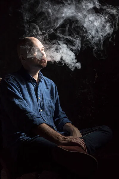 Hombre calvo maduro fumando, retrato sobre fondo negro. — Foto de Stock