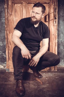 Olgun sakallı adam klasik kapının arkasında oturuyor.