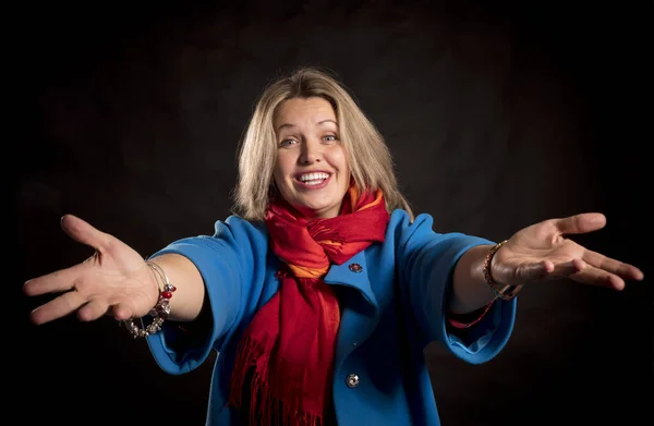 Veselá 40-letá žena v modrém kabátě a červeném šátku uvítací gesto — Stock fotografie