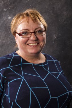 Mavi elbiseli orta yaşlı kadın gülümsüyor.