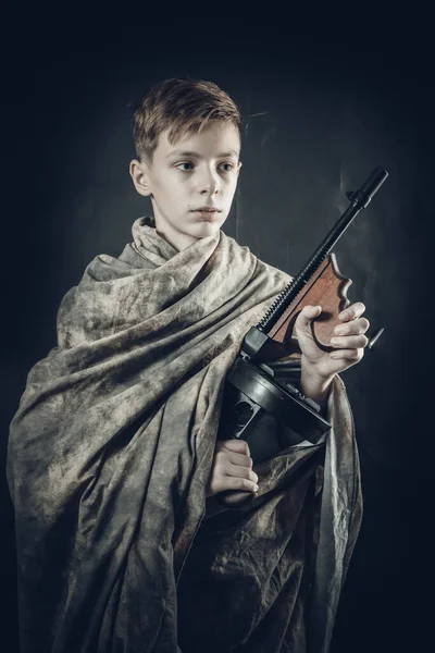 Tenn menino vestido com roupão de camuflagem com uma arma jogando soldado — Fotografia de Stock