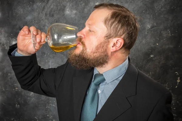 Vaste bebaarde man in pak proeft whisky in een glas — Stockfoto