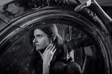 Genç, uzun saçlı, güzel kadın klasik aynanın önünde oturuyor.