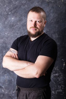 Tişört stüdyo resmi giymiş sakallı bir adam.