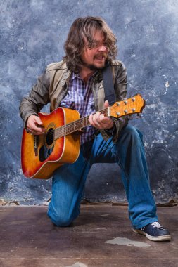 Olgun müzisyen akustik gitar stüdyo portresi çalıyor..