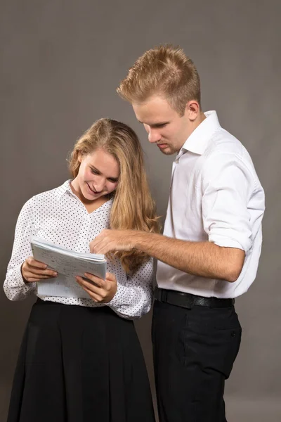 Twee studenten jonge man en vrouw kijken naar kranten — Stockfoto