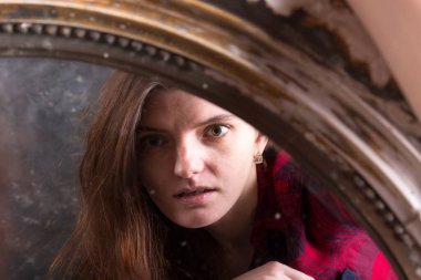 Genç, uzun saçlı, güzel kadın klasik aynanın önünde oturuyor.