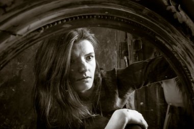 Genç, uzun saçlı, güzel kadın klasik aynanın önünde oturuyor.